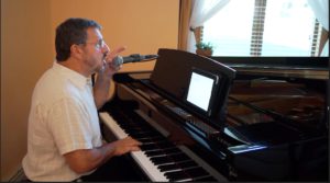 A man sitting at the piano with a microphone.