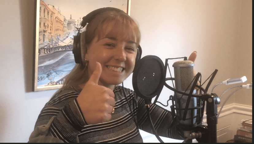 A woman with headphones on giving the thumbs up.