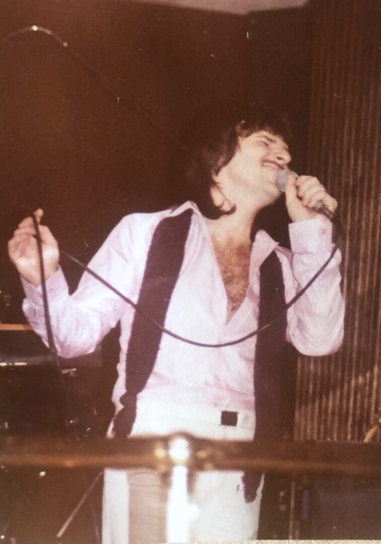 A man singing into a microphone in front of a crowd.