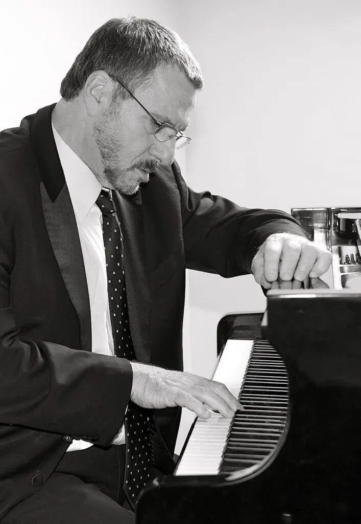 A man in suit and tie playing piano.